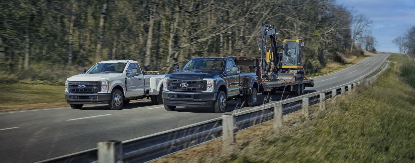 White 2025 Ford F-350 XL and black F-450 XL driving on a highway